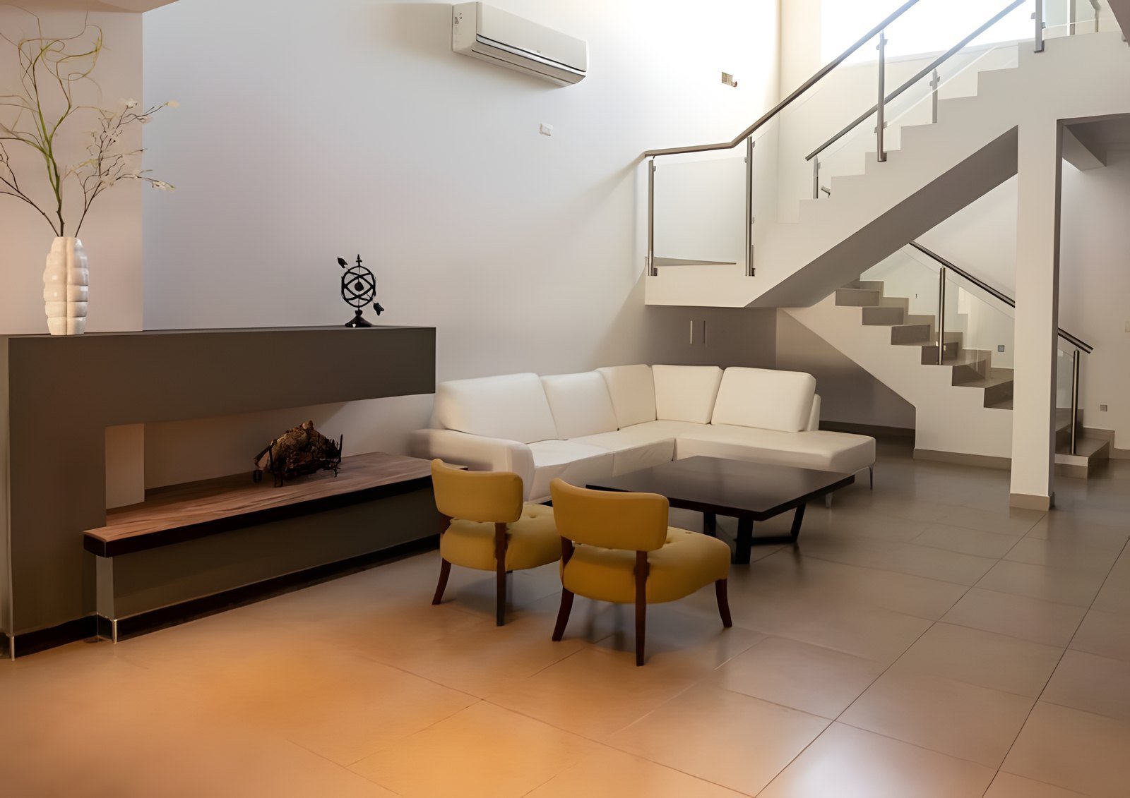 Living con sillón en L y escalera de acero inoxidable y vidrio