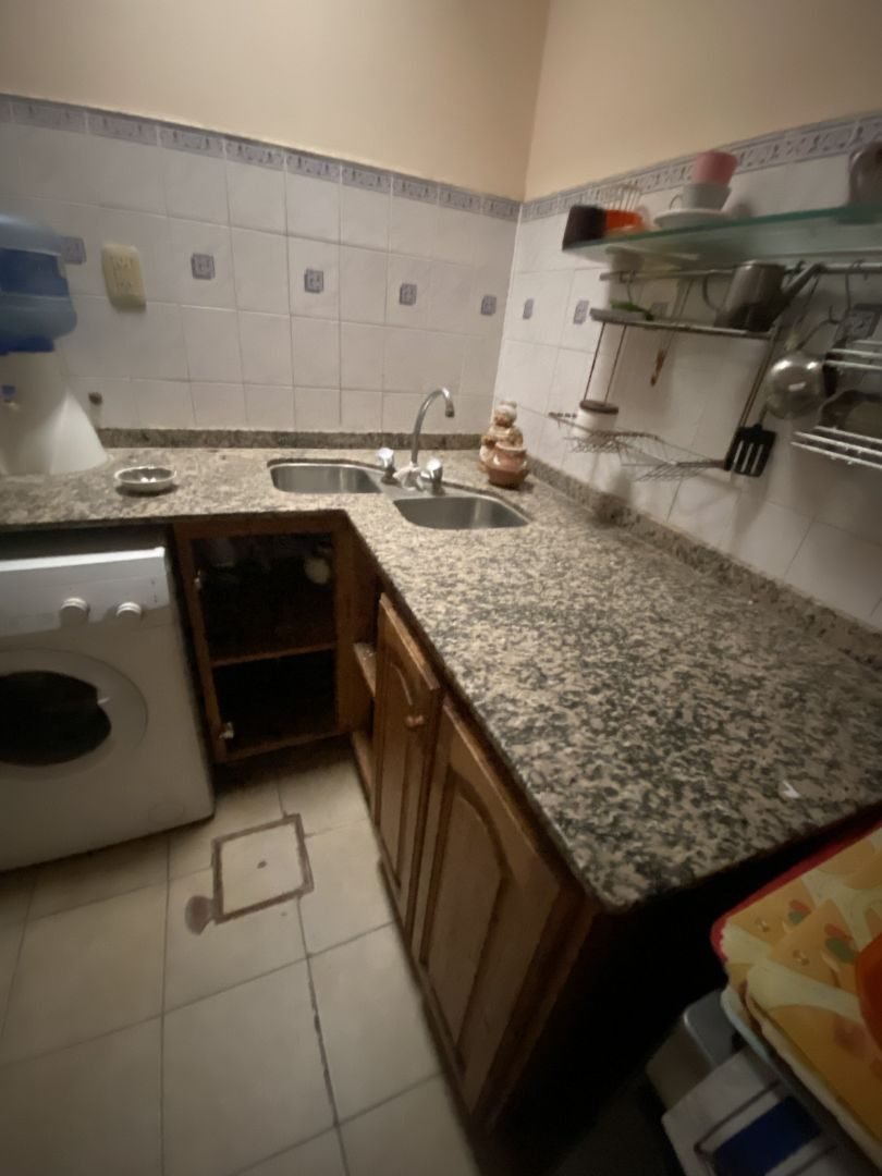 Cocina con mesada de granito, bajo mesada de madera y lugar para el lavarropas