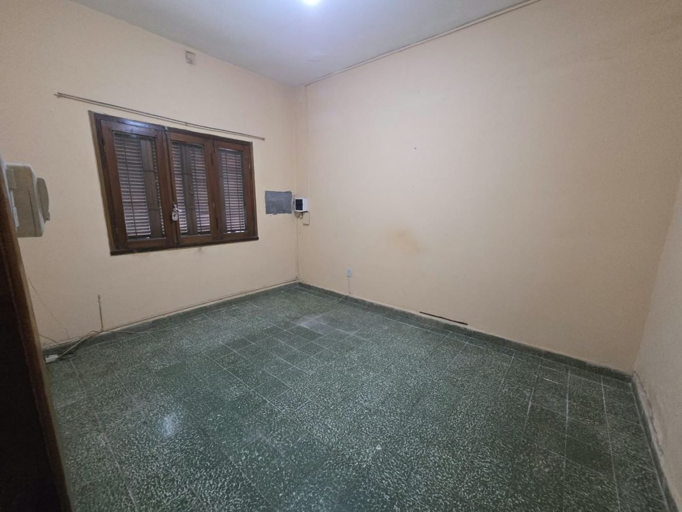 Dormitorio con ventana de madera y postigos