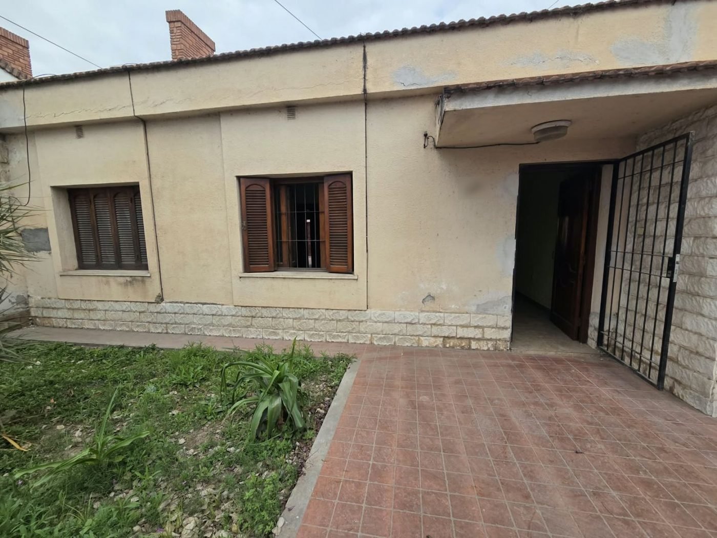 Frente de la casa con ventanas de madera y jardín