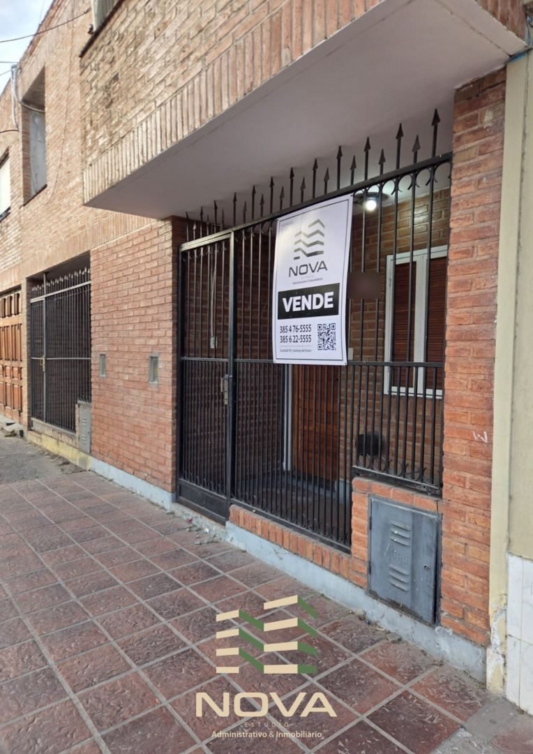 Frente del dúplex de ladrillo visto sobre calle Moreno, con rejas y cartel de NOVA