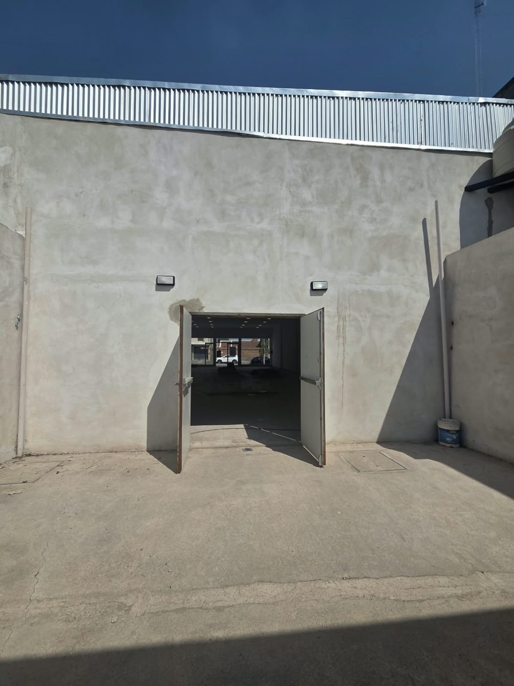 Acceso trasero al salón del local, con puerta doble abierta y vista al frente vidriado