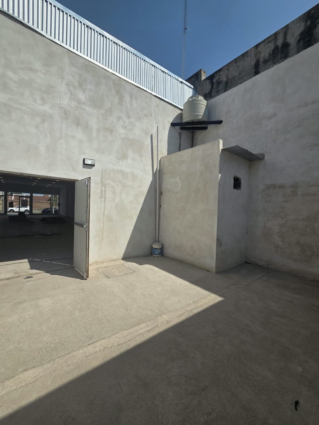 Patio trasero del local con puerta de salida de emergencia hacia el salón