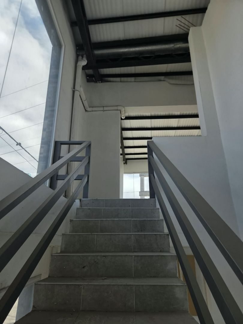 Escalera de acceso a la planta alta, con baranda metálica