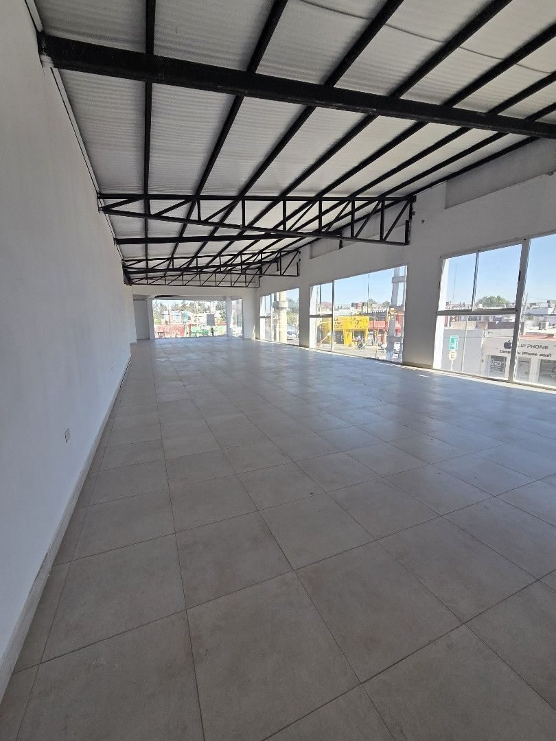 Salón en planta libre con piso cerámico y ventanales